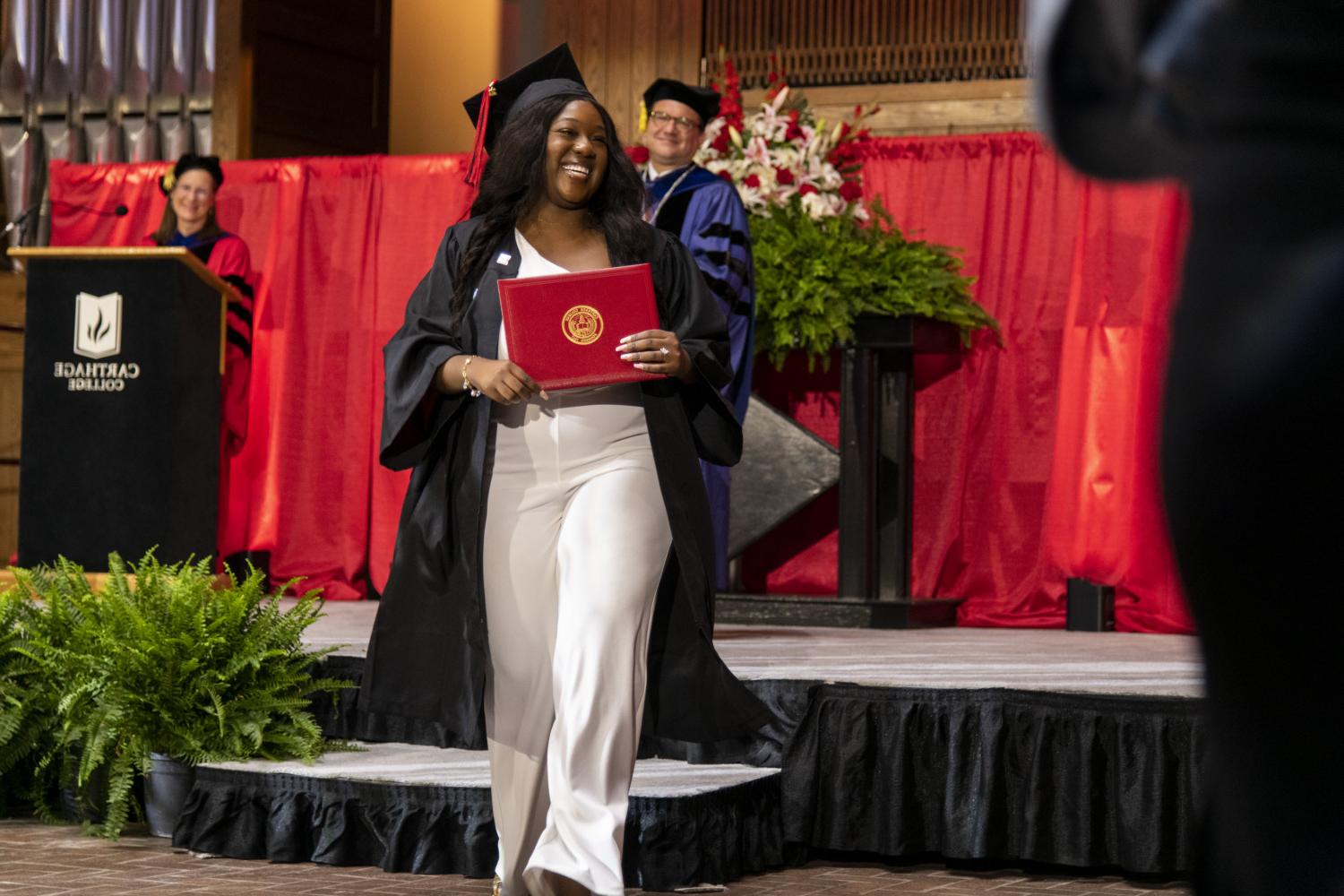 A 2023 <a href='http://kuo2.mogrenlandscape.com'>BETVLCTOR伟德登录</a> graduate beams as she leaves the Commencement stage after receiving her diploma from Carthage President John 吞下.